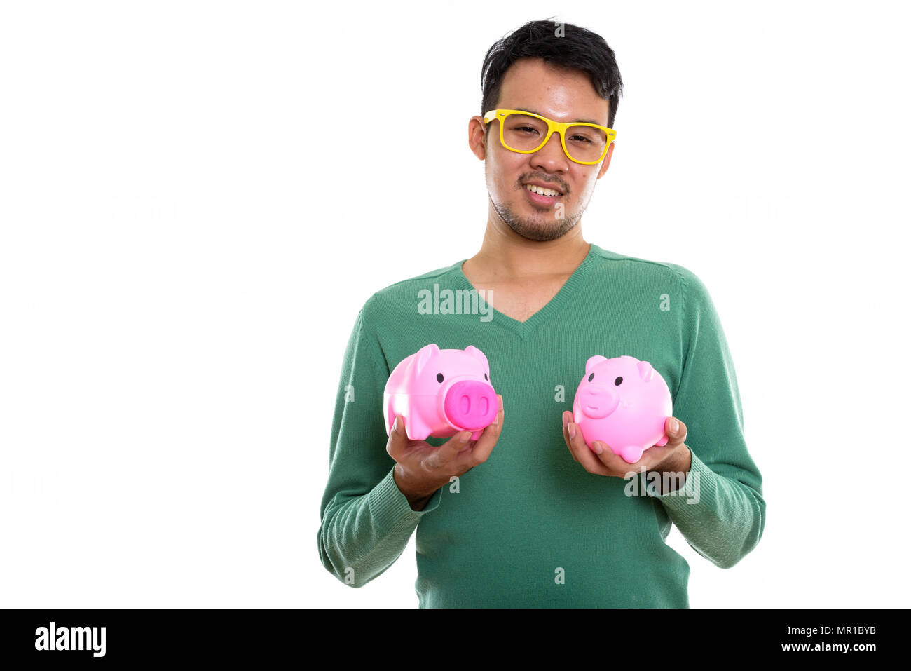 Studio shot of young happy Asian man smiling while holding two p Stock Photo