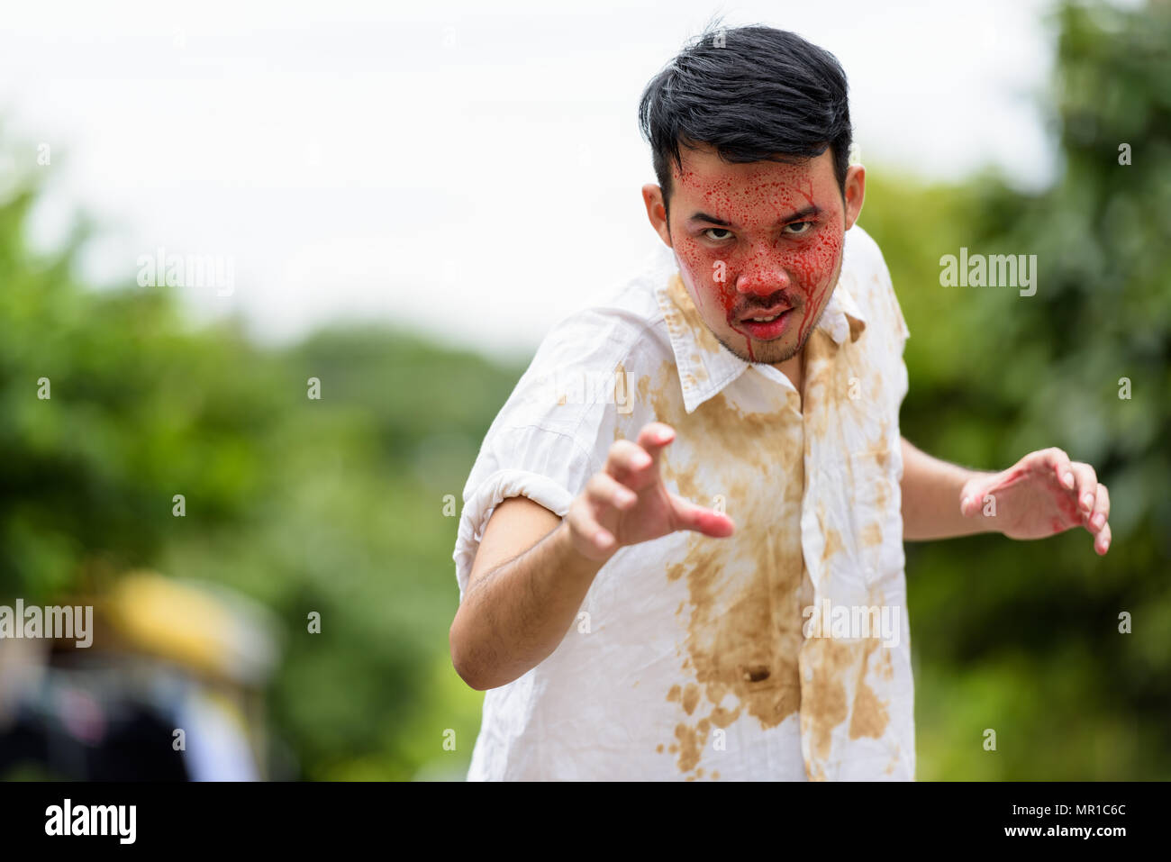 Young happy crazy Asian man smiling ready to kill with blood on  Stock Photo