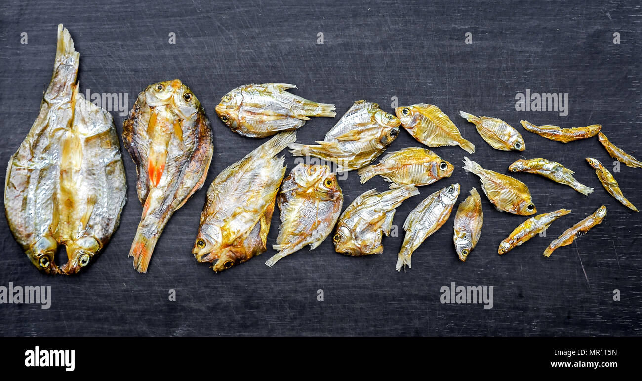 Dry fish and sunny on black wooden floor, small dried fish and pattern ...