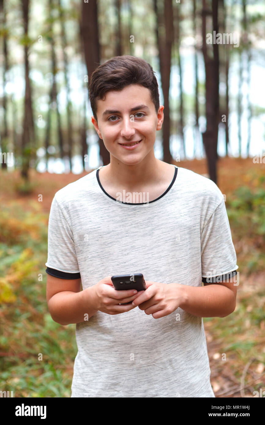 Cool teenager with sixteen years old and a mobile in a forest Stock
