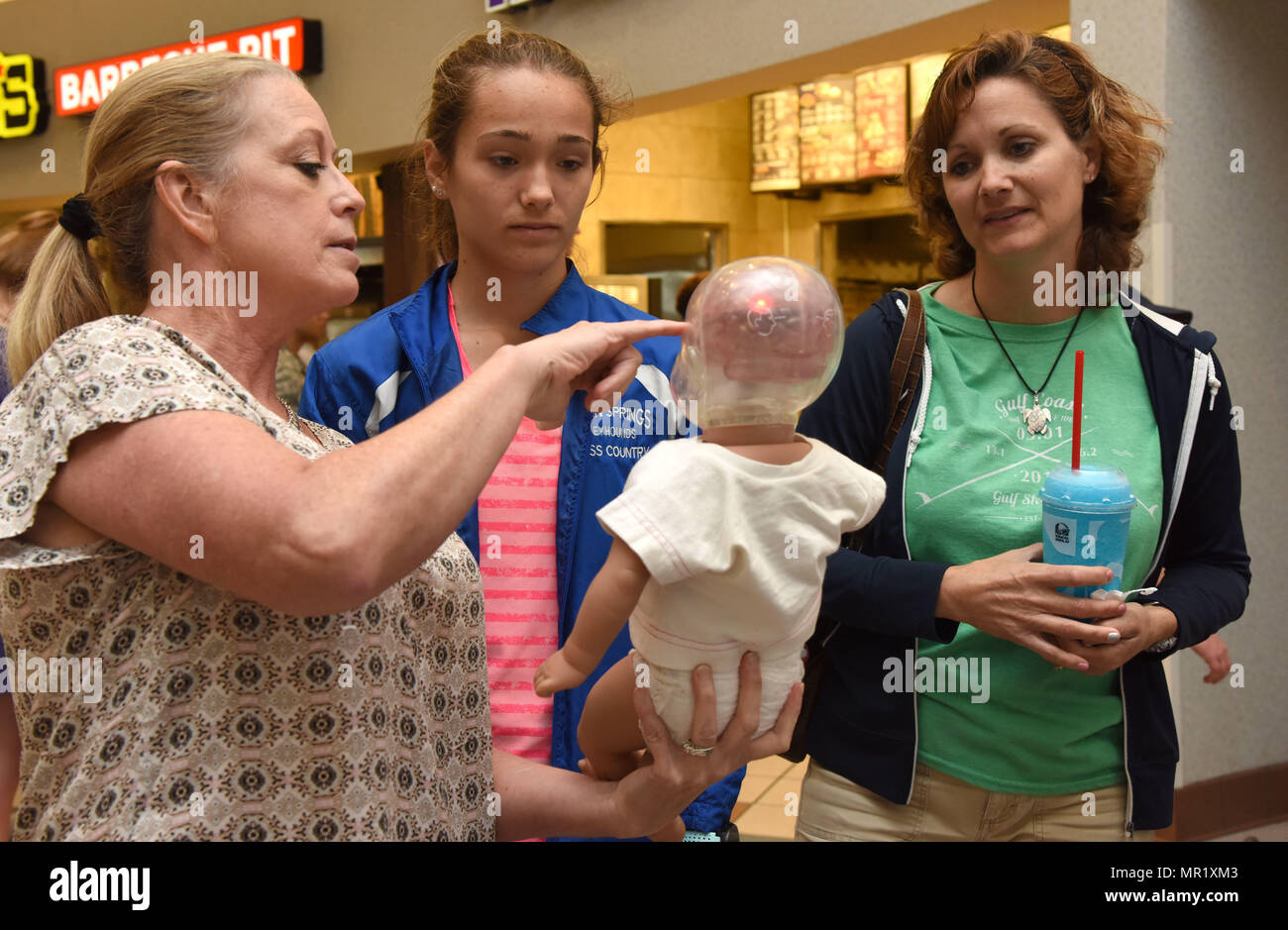 Paula Spooner, 81st Medical Operations Squadron family advocacy outreach manager, provides a shaken baby syndrome simulation to Isabelle and Lori Wheeler in the base exchange April 21, 2017, on Keesler Air Force Base, Miss. The family advocacy staff manned a booth with hand-outs and reading material about child abuse prevention for Keesler personnel in recognition of Child Abuse Prevention Month. (U.S. Air Force photo by Kemberly Groue) Stock Photo