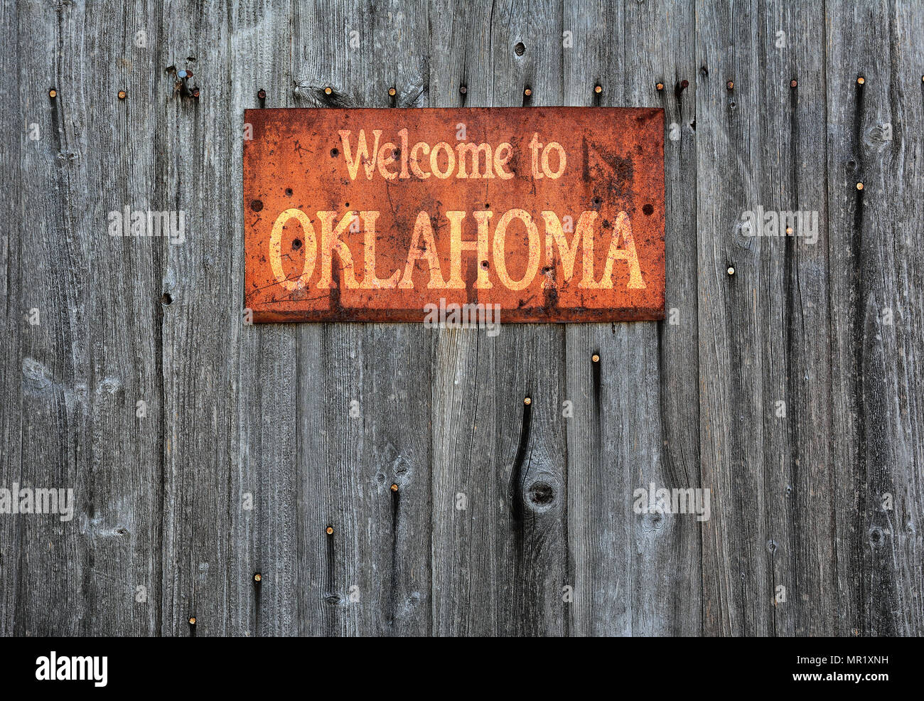 Rusty metal sign on wooden wall with the phrase: Welcome to Oklahoma. Stock Photo