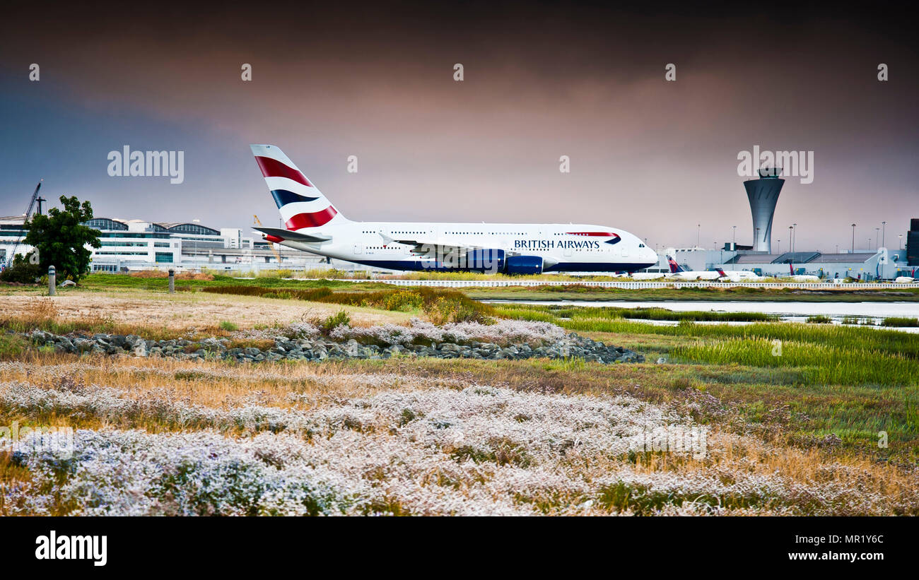 world's largest passenger aircraft,taxis to takeoff position,at San Francisco international airport,seen from across marshland against dramatic sky, Stock Photo