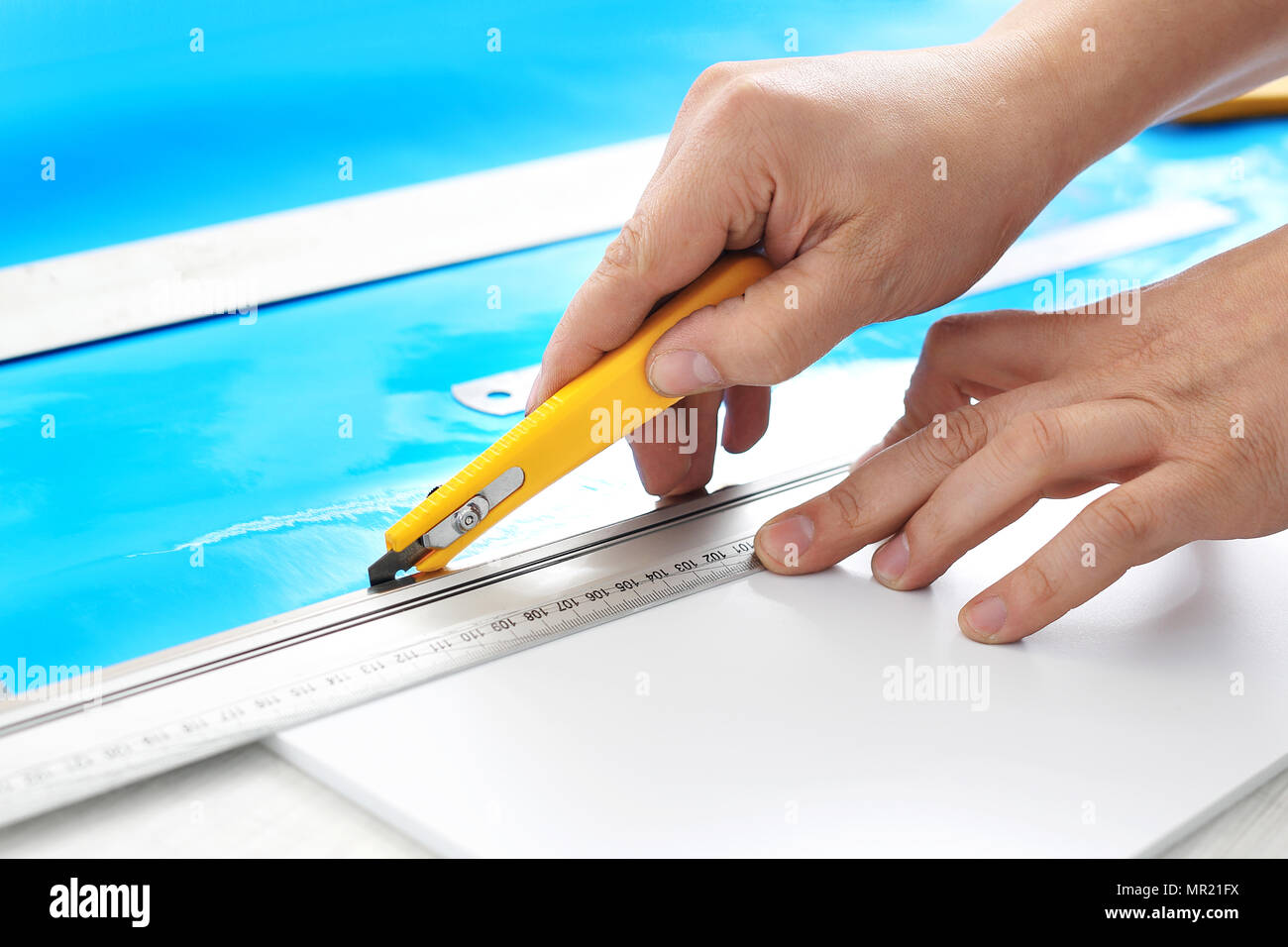 Advertising studio. The employee cuts the foil with a knife Stock Photo