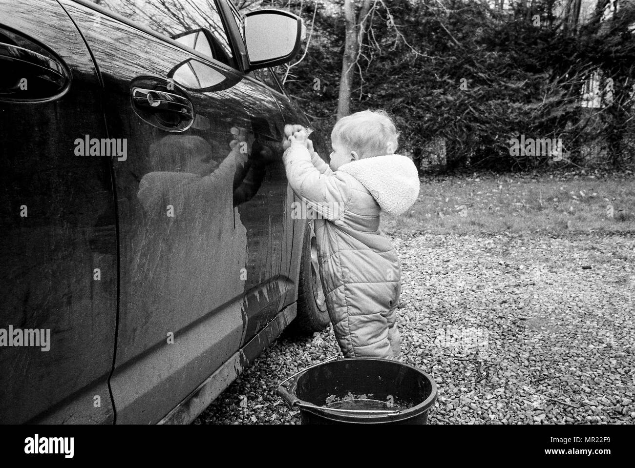 Baby boy, one year old (20Months) washing a car with a sponge. Stock Photo
