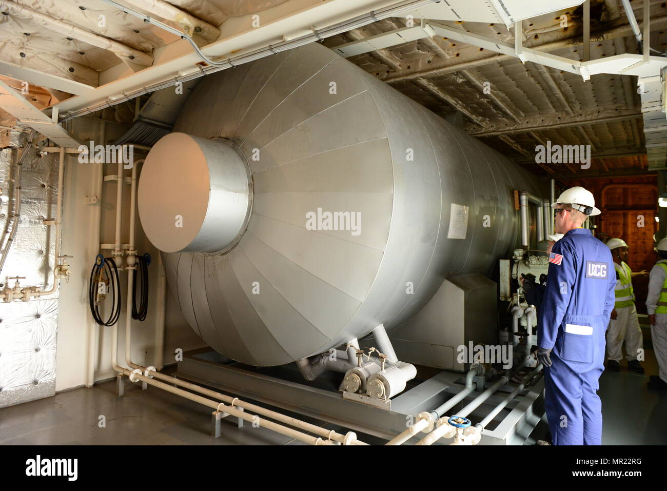 Petty Officer 1st Class Eric Kelley, a marine science technician at Coast Guard Marine Safety Unit Portland, stands next to a low-pressure C02 system tank aboard the vessel Morning Catherine during a Port State Control exam at the Port of Portland, Portland, Ore., May 1, 2017.     Kelley checks the general condition of the tank, specifically if there is any ice or frost build up, which might indicate a leak in the tank or faulty insulation. Stock Photo
