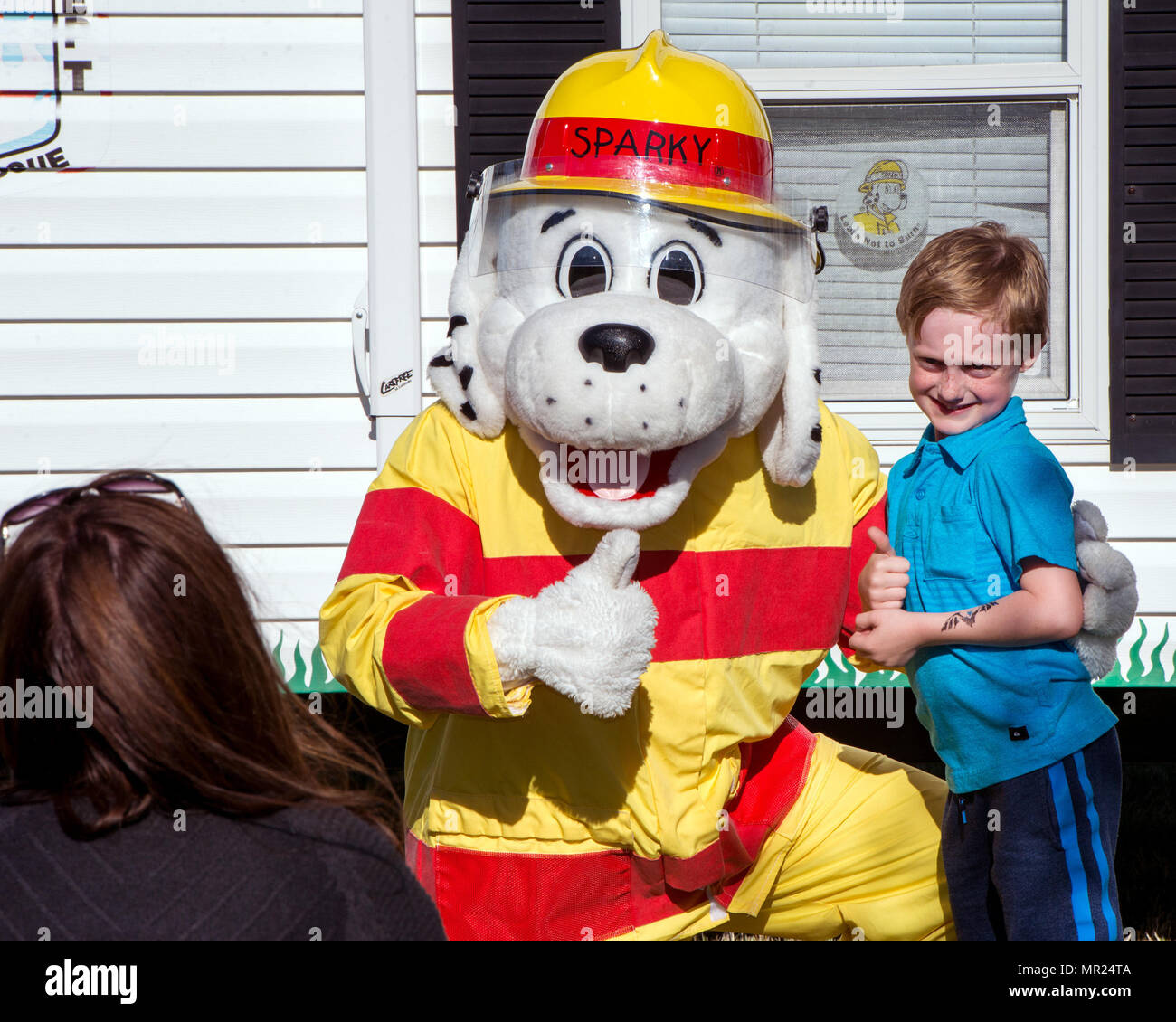 A child poses for a photo with “Sparky the Dog” during the Autism ...