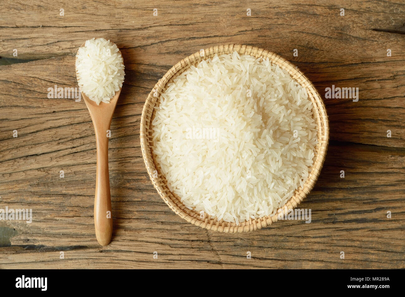 white rice in wicker basket with spoon on wooden background Stock Photo