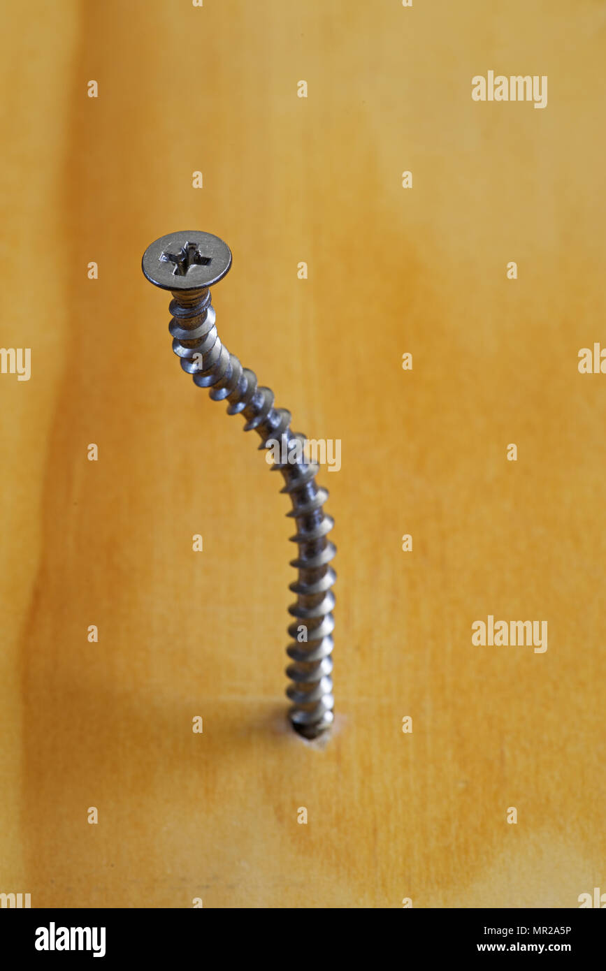 side view of a spiral bent screw in a wood board Stock Photo