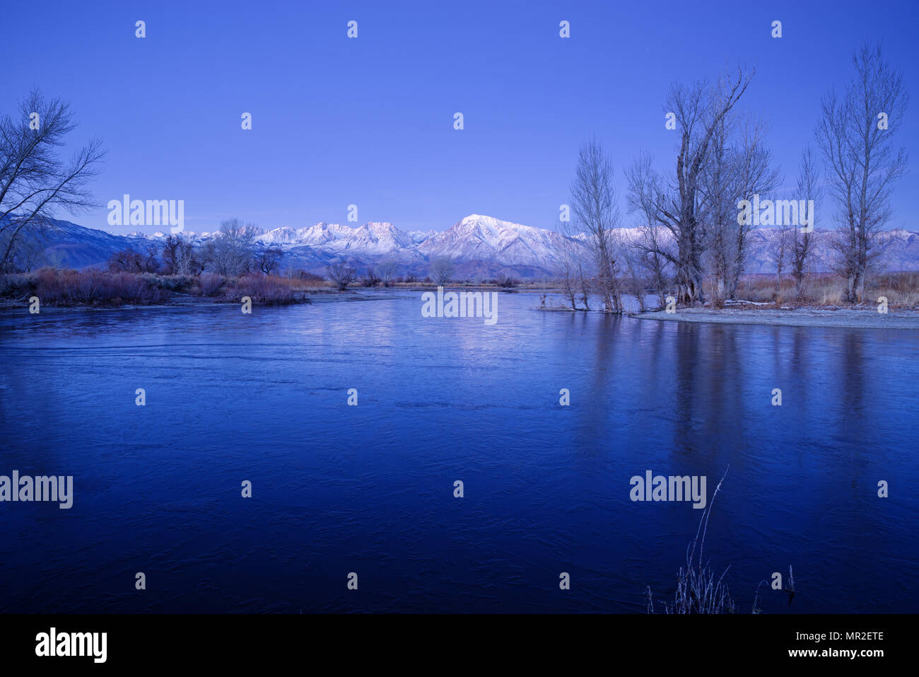 a frozen pond in the winter before sunrise with distant mountains Stock Photo