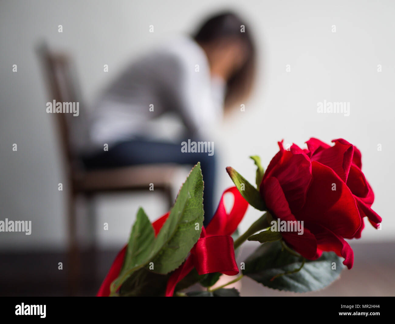 Sad woman sitting and crying with red rose in focus. Lonly , love ...