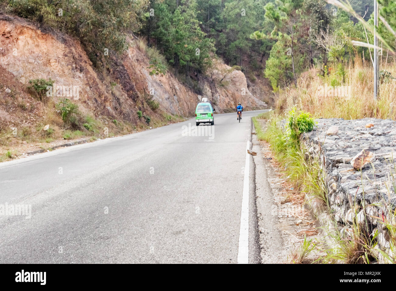 San Jose Arada, Guatemala - December 3, 2016: Car is passing man riding on bicycle on the countryside of Guatemala near San Jose Arada. Stock Photo
