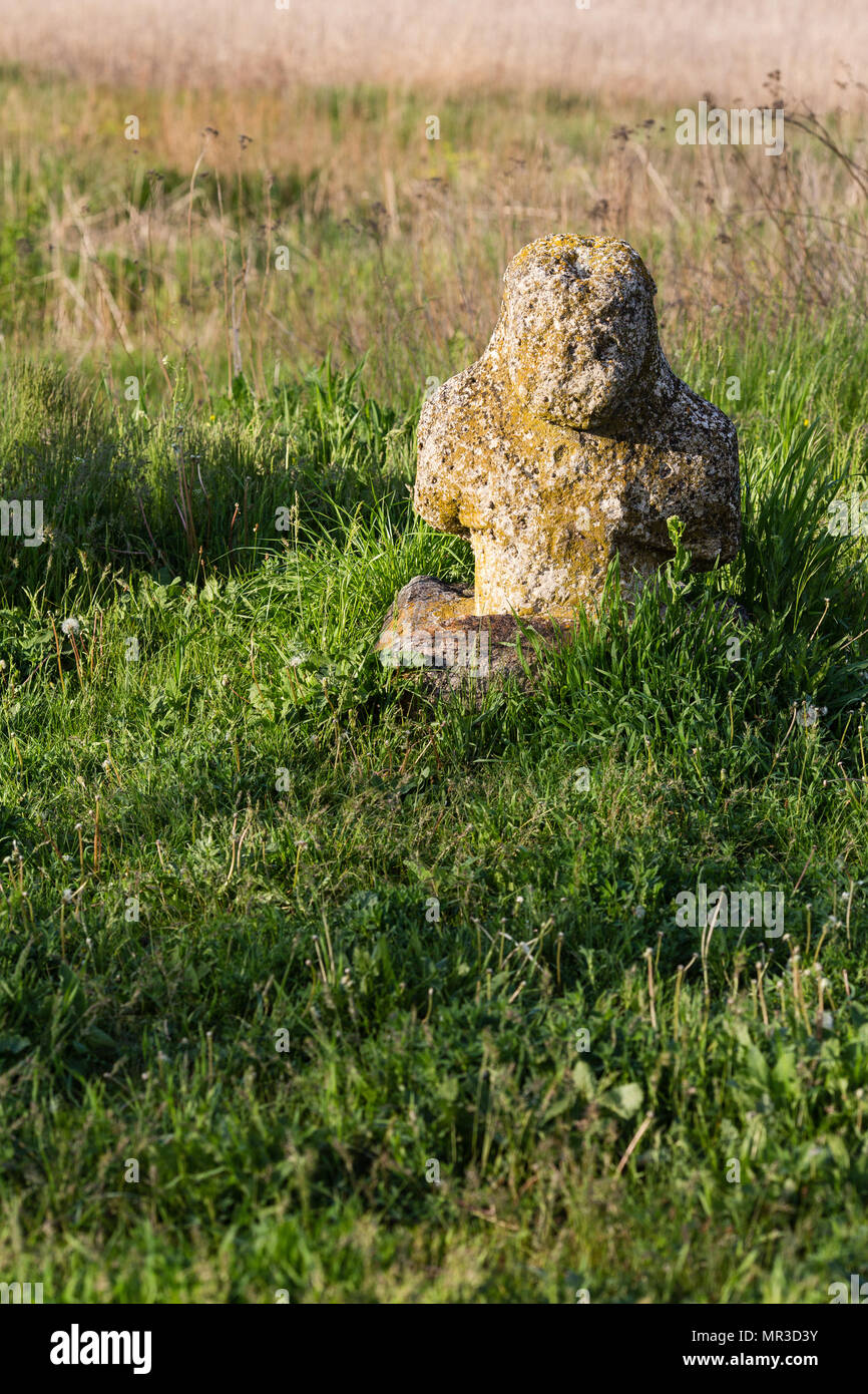 Historical Scythian monuments called kurgan stelae standing in nature against bright green grass, blue sky with clouds Stock Photo