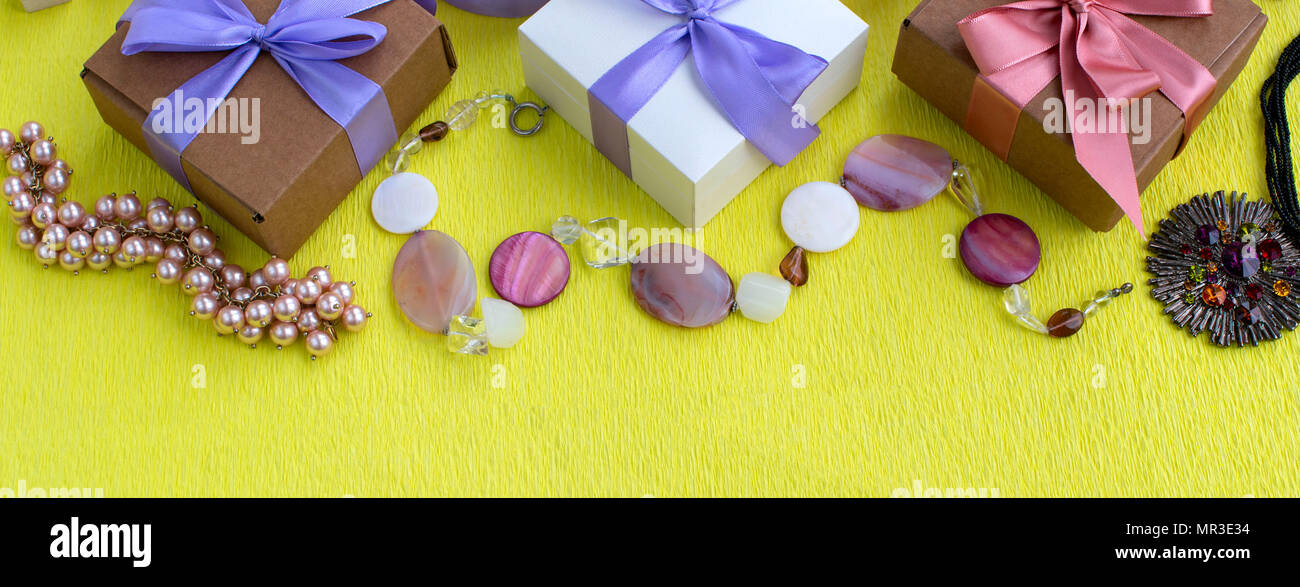 Banner Three decorative boxes with gifts on yellow Satin ribbon bow background. Women's jewelry Fashion accessories. Flat lay top view Stock Photo