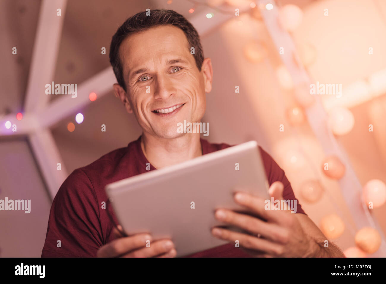 Delighted handsome man using modern device Stock Photo