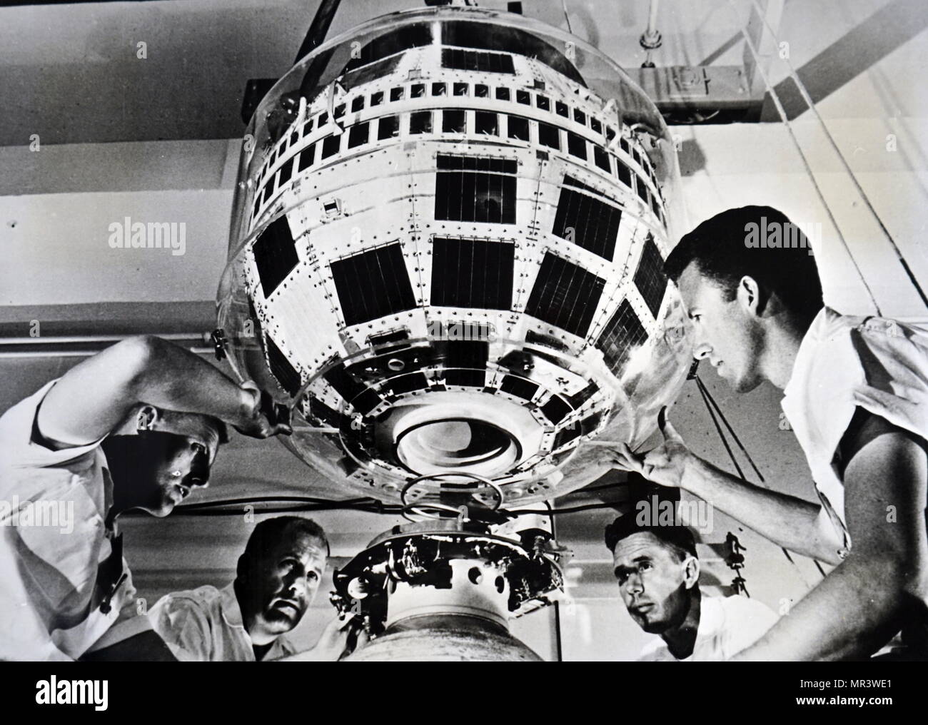 Photograph taken during the production of the Thor-Delta rocket. Technicians mate the Telstar communications satellite to the third stage of the rocket. Dated 20th century Stock Photo