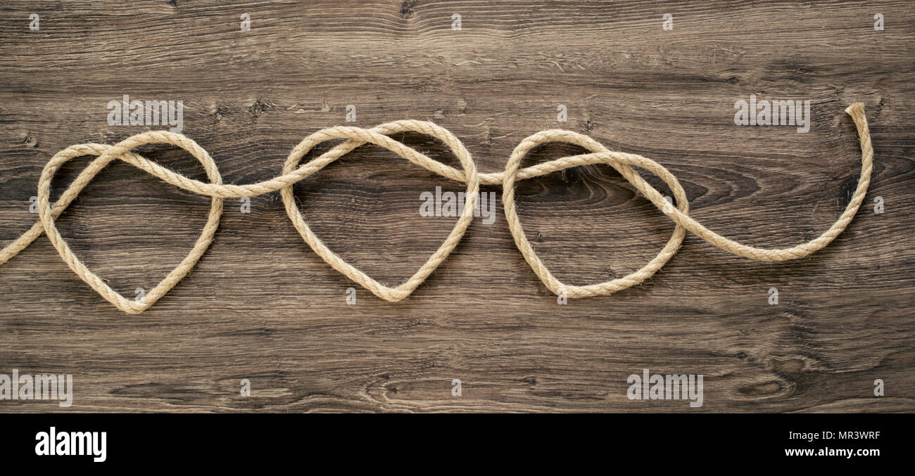 Three heart rope shapes on old wood Stock Photo