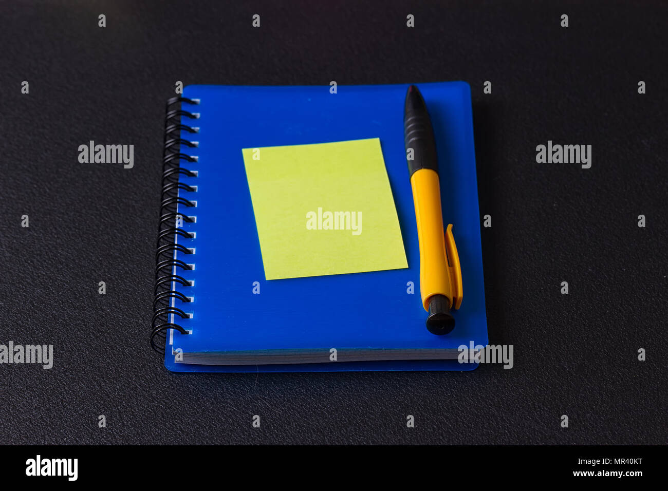 Blue notepad with multi-colored stickers and pen on a black background Stock Photo