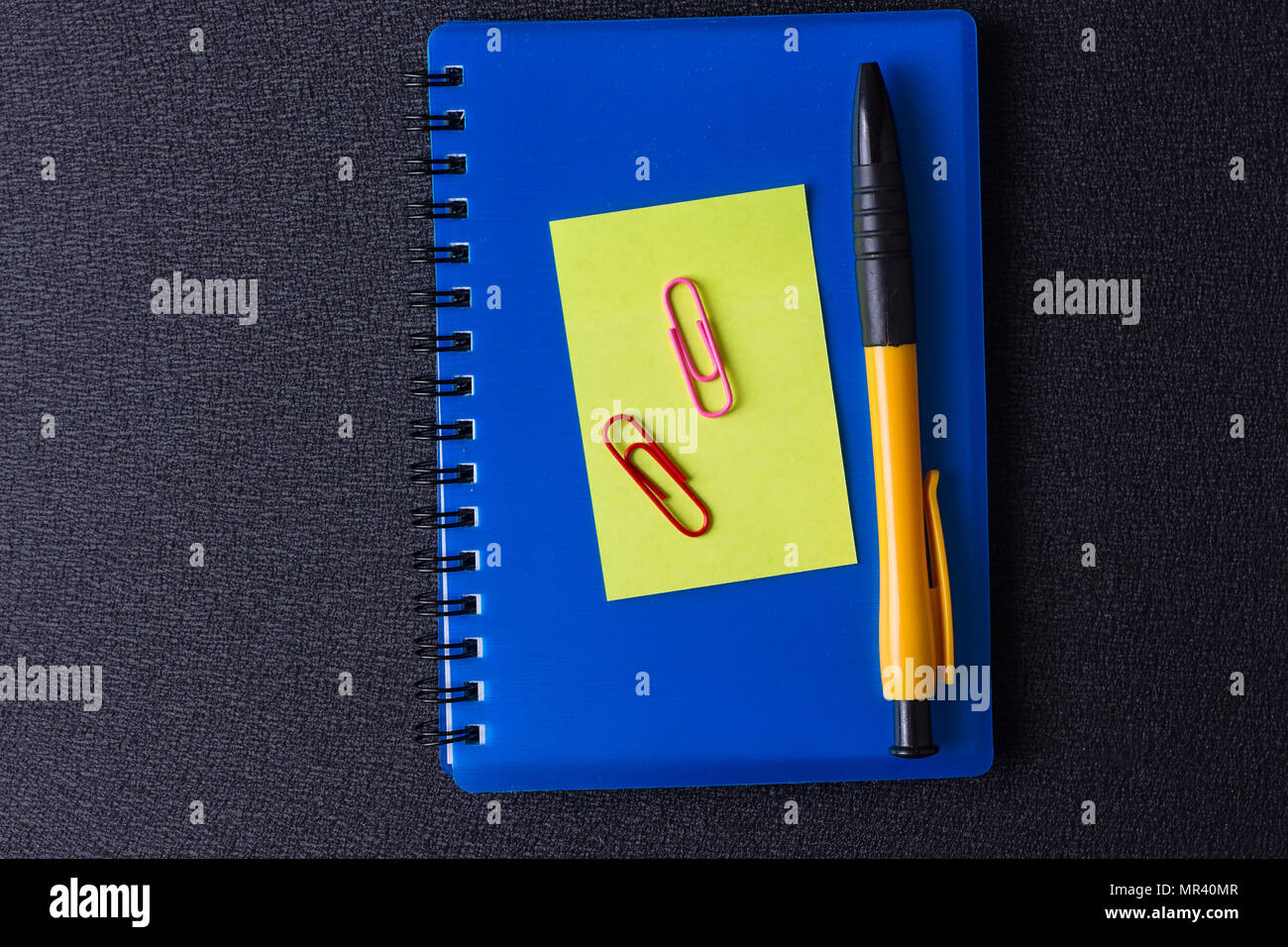 Blue notepad with multi-colored stickers and pen on a black background Stock Photo