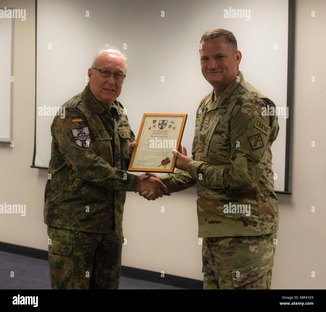 U.S. Army Brig. Gen. William E. King IV, Commander of the 20th CBRNE Command, receives an award from Col. Henry Neumann, Bundeswehr CBRN Commander, Satsop , Wash., May 2, 2017. Dragon fire is a bilateral exercise between the 48th Chemical, Biological, Radiological, and Nuclear (CBRN) Brigade and the German Bundswehr CBRN Defense command. It also serves as the culmination training event and validation exercise for the 22nd CBRN Battalion. (U.S. Army Pfc. Dra'corius White) Stock Photo