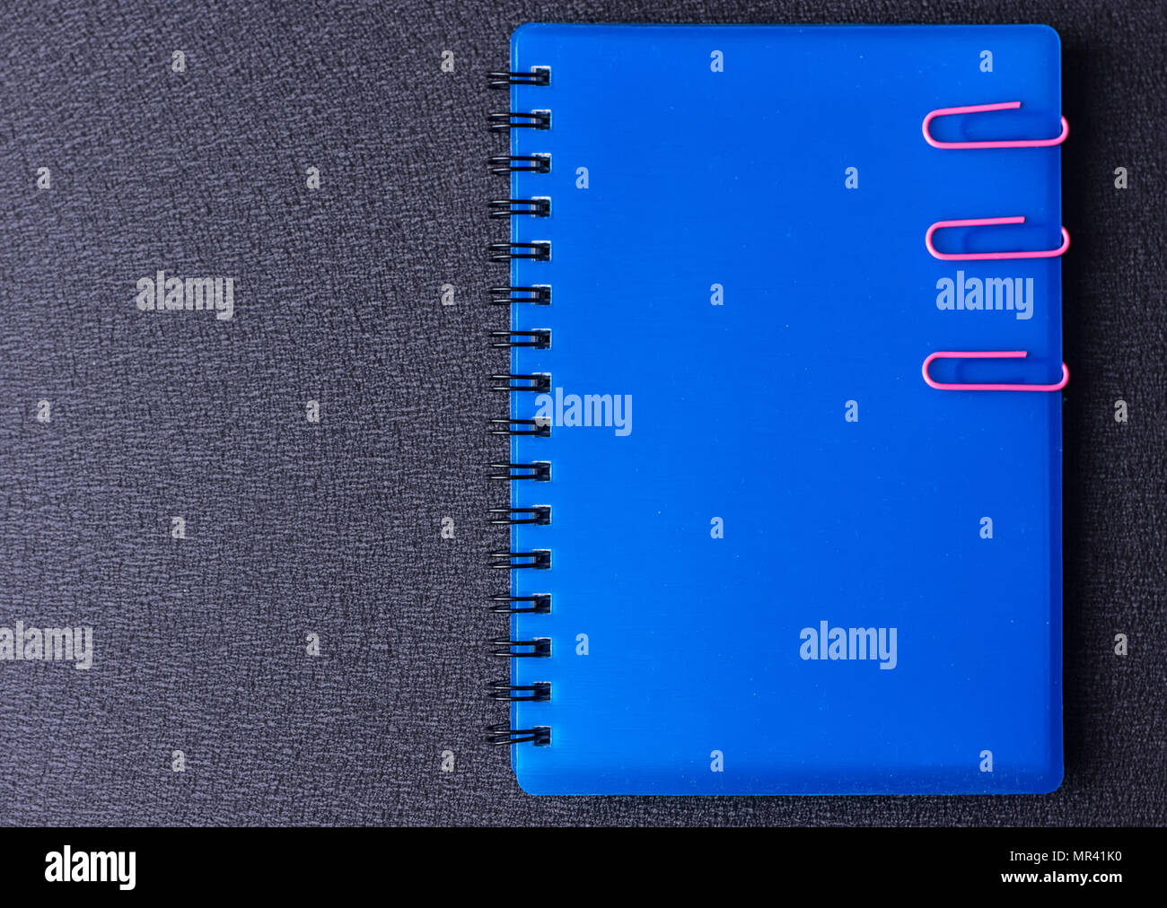 Blue notepad with paper clips on a black background Stock Photo