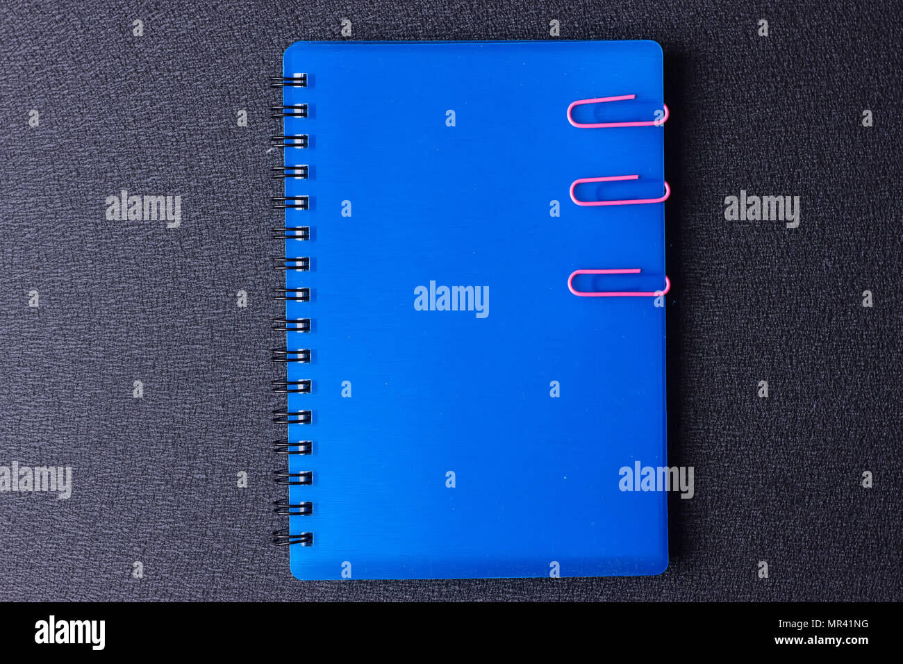 Blue notepad with paper clips on a black background Stock Photo