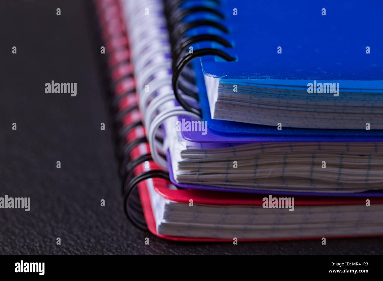 Several multi-colored notebooks on a spiral on a black background Stock Photo