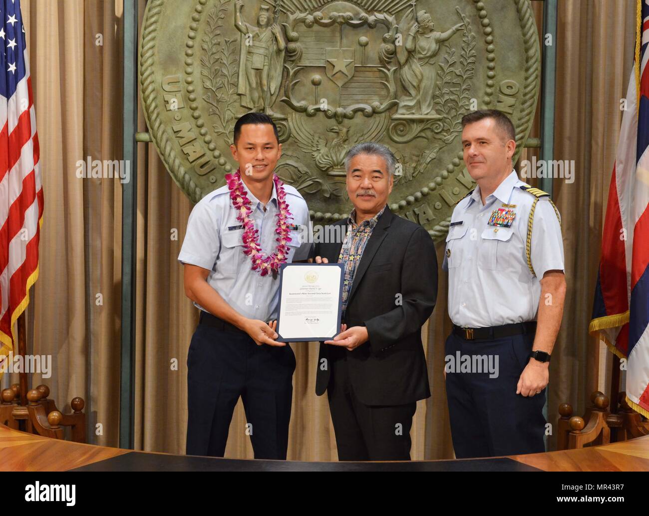 Petty Officer 2nd Class Scott Lee, a boatswain’s mate stationed at Coast Guard Station Honolulu, was recognized for his outstanding community service by Hawaii State Governor David Y. Ige and Capt. Brian Penoyer, Fourteenth Coast Guard District chief of staff, at the Hawaii State Capitol, May 5, 2017. The Military Affairs Council of the Chamber of Commerce Hawaii joined Governor Ige in a proclamation ceremony designating May as Military Appreciation Month and honoring service members from all five branches of the armed forces for their community service contributions. (U.S. Coast Guard photo b Stock Photo