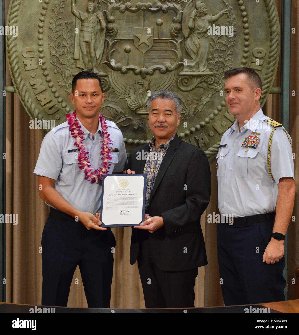 Petty Officer 2nd Class Scott Lee, a boatswain’s mate stationed at Coast Guard Station Honolulu, was recognized for his outstanding community service by Hawaii State Governor David Y. Ige and Capt. Brian Penoyer, Coast Guard Fourteenth District chief of staff, at the Hawaii State Capitol, May 5, 2017. The Military Affairs Council of the Chamber of Commerce Hawaii joined Governor Ige in a proclamation ceremony designating May as Military Appreciation Month and honoring service members from all five branches of the armed forces for their community service contributions. (U.S. Coast Guard photo b Stock Photo