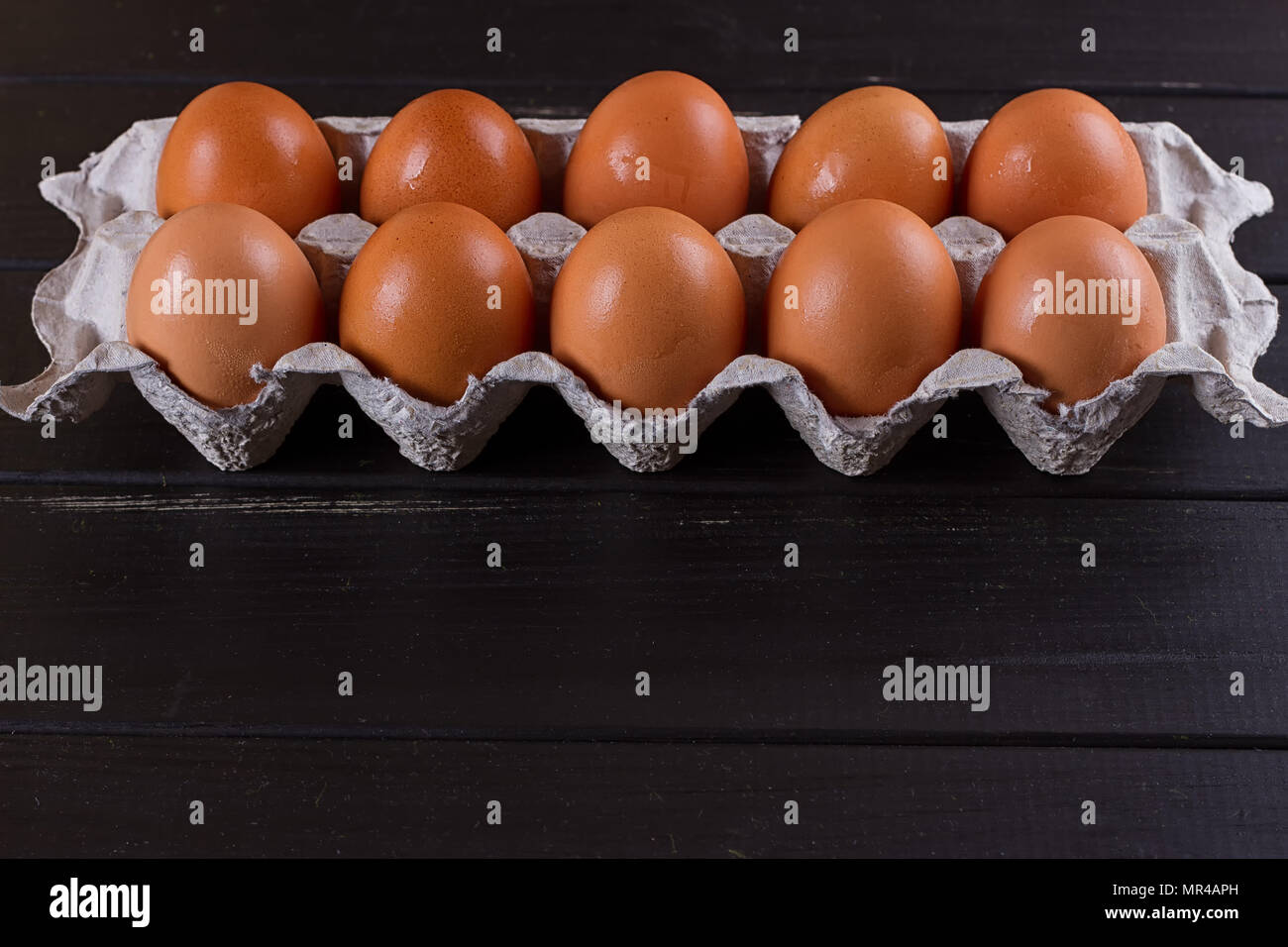 Cardboard egg box on black wooden background. Eggs container Stock