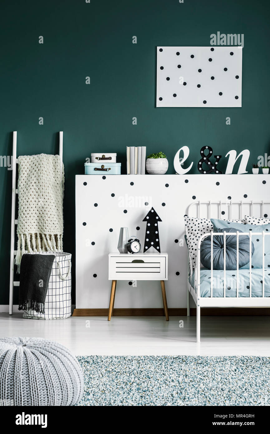 Polka dot poster on a dark green wall in a scandinavian style white bedroom interior for a teenager Stock Photo