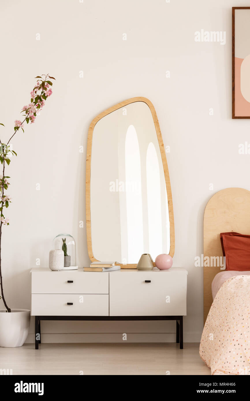 Wooden mirror on white cabinet in minimal dressing room interior. Real photo Stock Photo