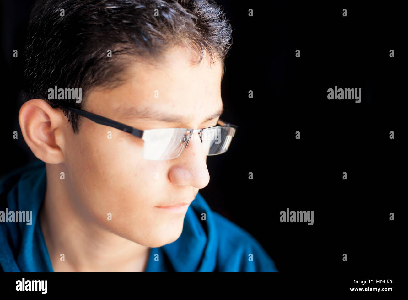Portrait Of Young Teenager Boy Wearing Half Rim Black Colored Reading Glass Or Spectacles And A Green Hooded T Shirt Posing In Black Dark Background L Stock Photo Alamy