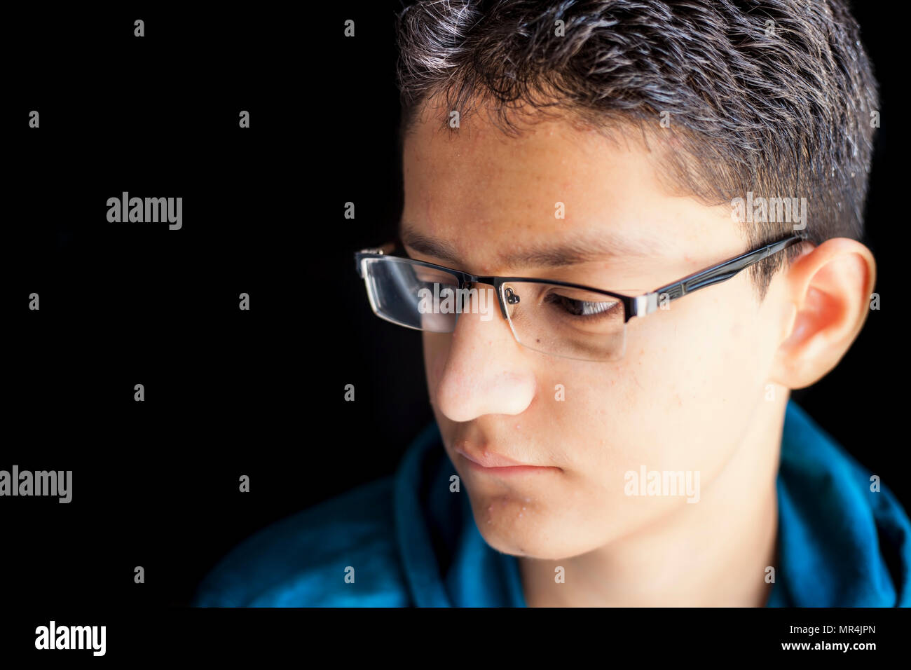Portrait Of Young Teenager Boy Wearing Half Rim Black Colored Reading Glass Or Spectacles And A Green Hooded T Shirt Posing In Black Dark Background L Stock Photo Alamy