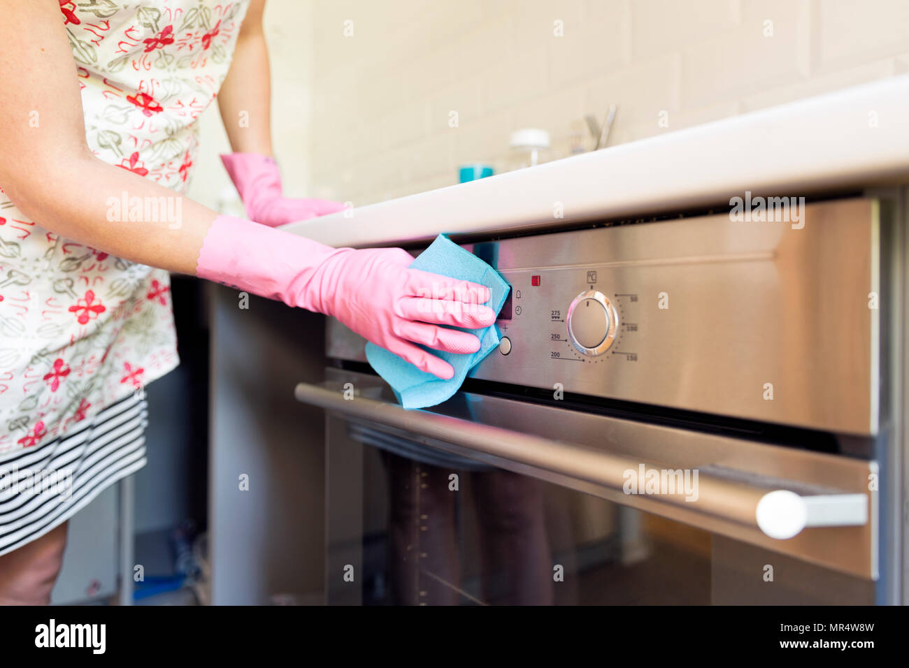 Woman's hand with pink protective gloves cleaning oven door. People, housework, cleaning concept Stock Photo