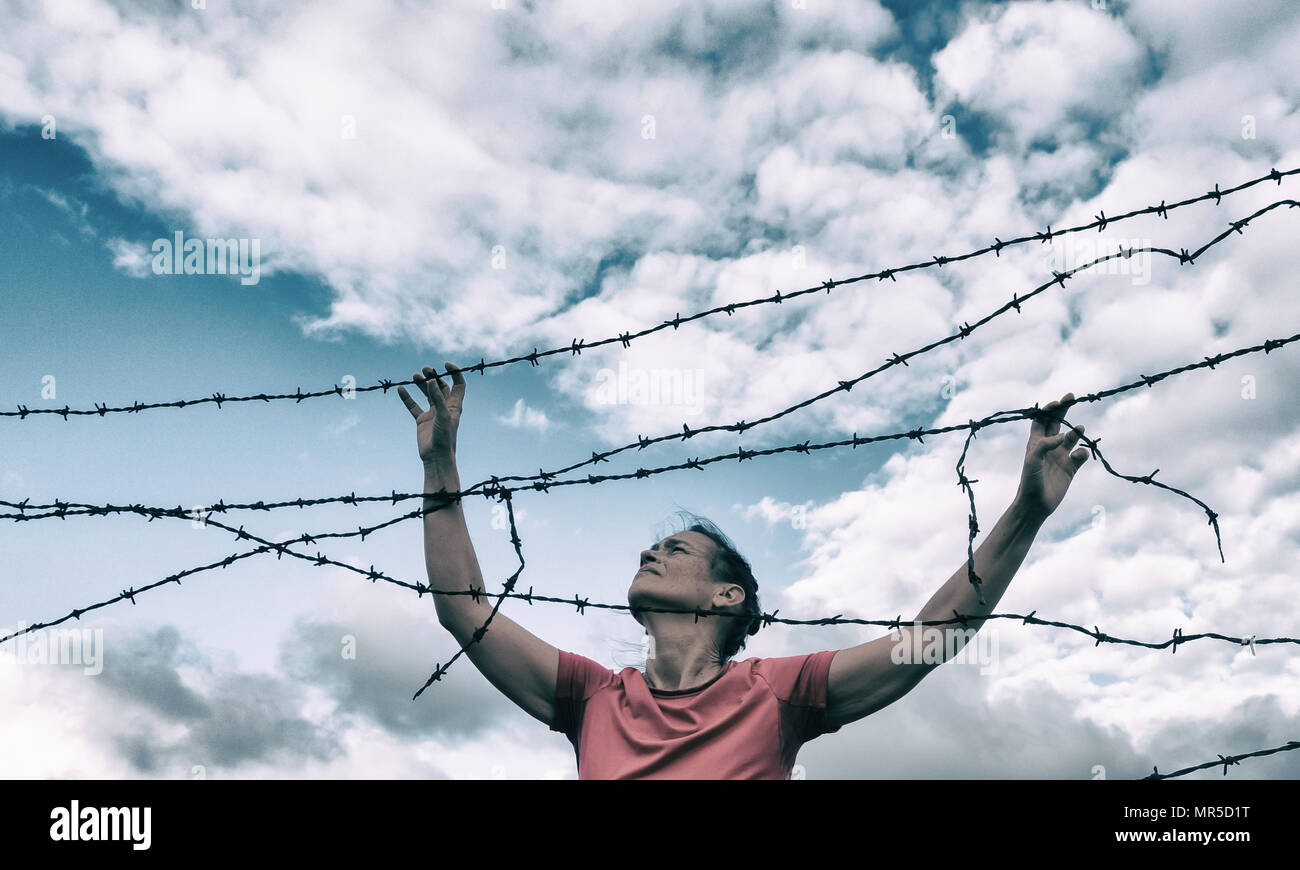Woman behind barbed wire fence: asylum, Brexit, illegal immigration, human trafficking/slavery...,concept image. Stock Photo