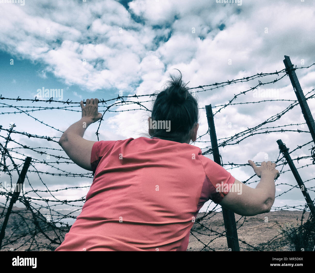 Woman behind barbed wire fence: asylum, Brexit, illegal immigration, human trafficking/slavery...,concept image. Stock Photo