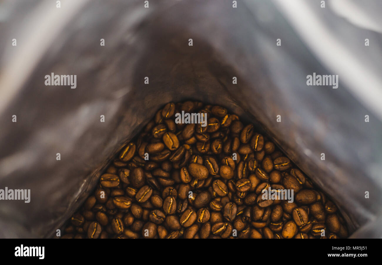 Silver bag of freshly roasted brown coffee beans from an organic farm in Colombia Stock Photo
