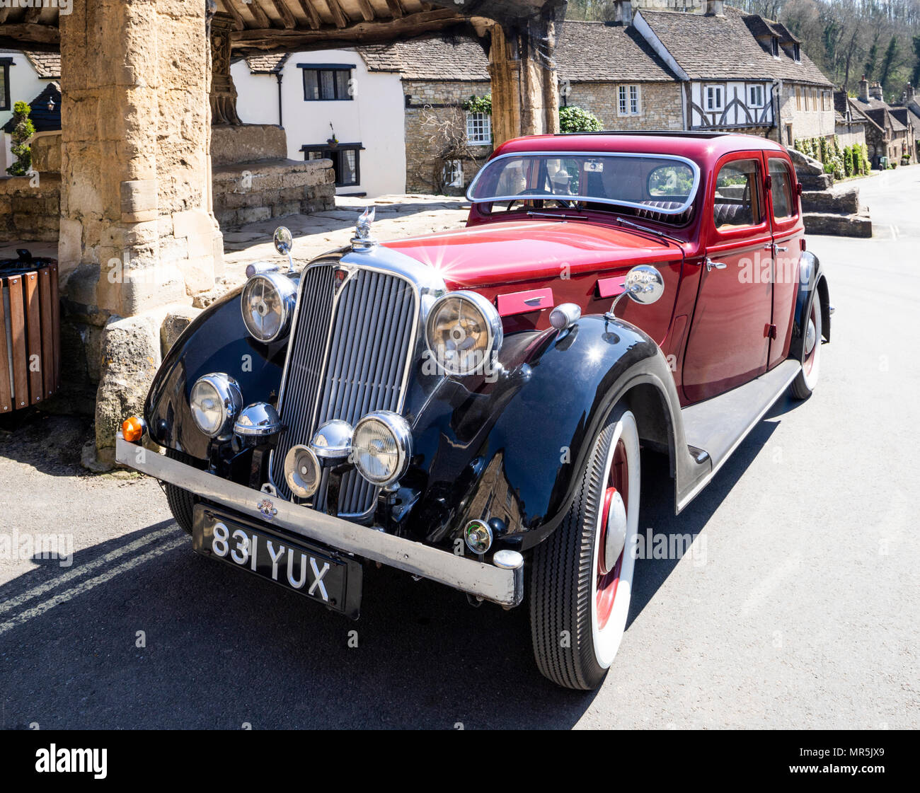 A red Rover 16 parked beside the market cross in the south Cotswold village of Castle Combe, Wiltshire UK Stock Photo
