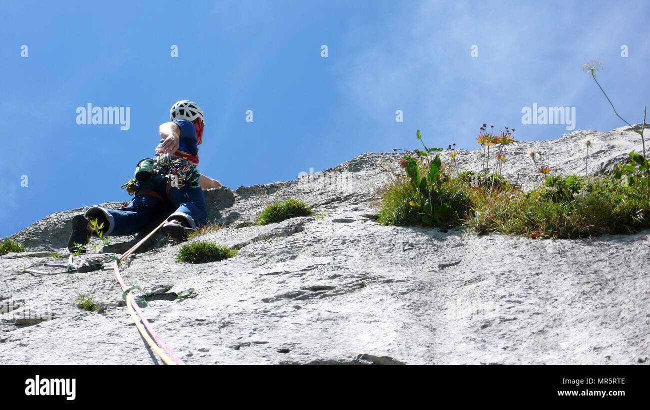 mountain guide climbing a steep slab pitch of a hard rock climbing route in the Alps of