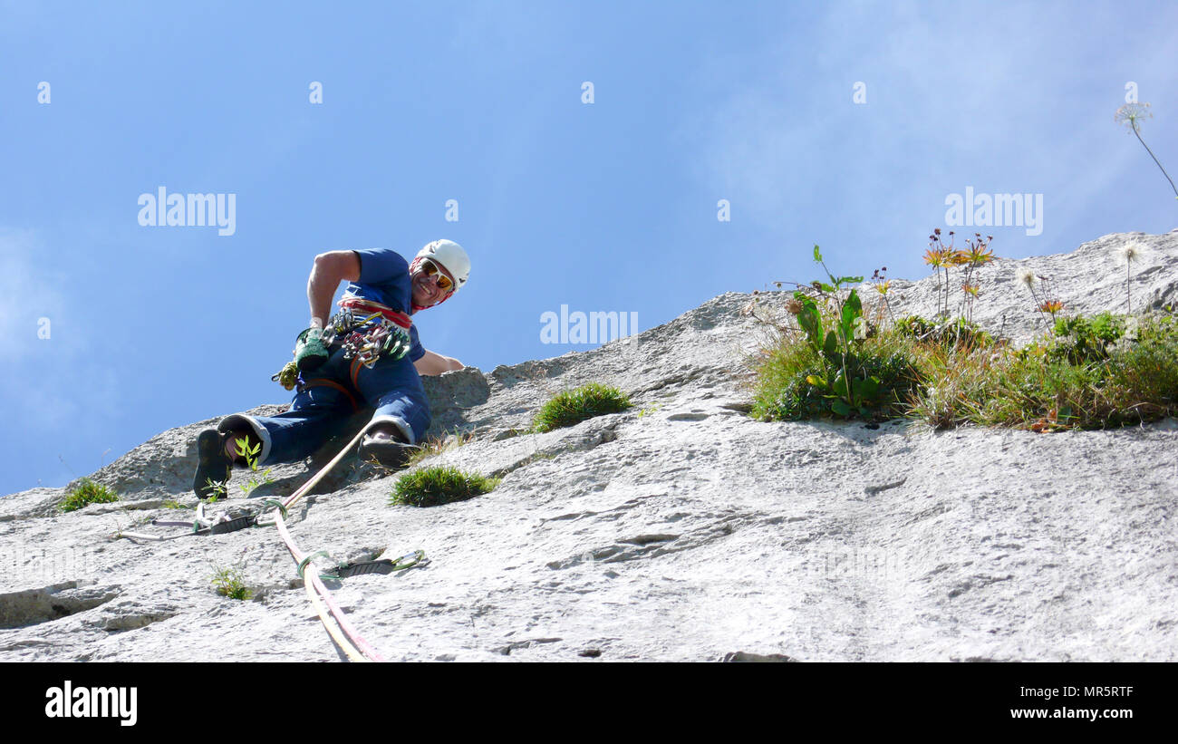 mountain guide climbing a steep slab pitch of a hard rock climbing route in the Alps of