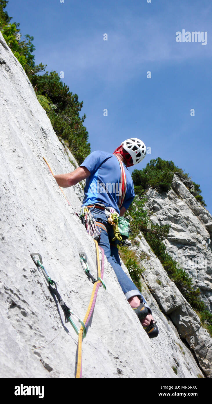 mountain guide climbing a steep slab pitch of a hard rock climbing route in the Alps of