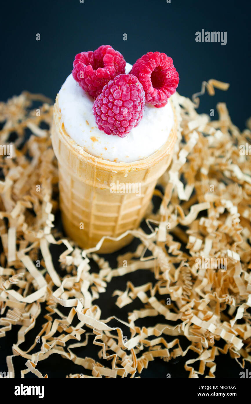 Ice cream with raspberry in waffle cone on wood Stock Photo