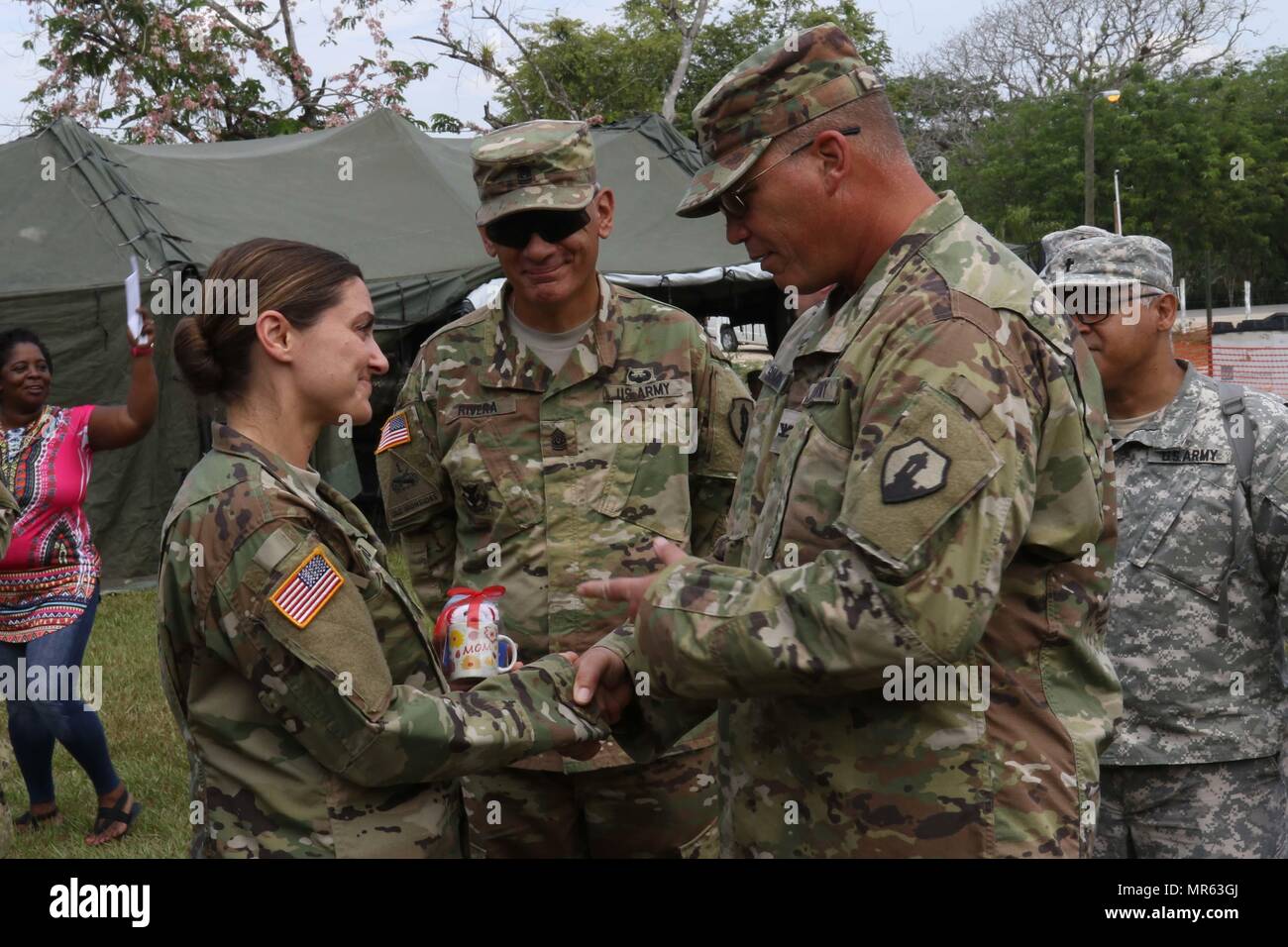 Command Sgt. Maj. Angel Rivera and Col. John Simma, both serving with the 210th Regional Support Group from Puerto Rico, present a Mother's day gift to Capt. Anne-Marie Octavio, who serves as a nurse practitioner for the Wyoming National Guard Medical Detachment. Octavio and a staff of medical professionals have been administering free health care during Beyond the Horizon 2017. (US Army Photo by Sgt. 1st Class Whitney Houston) Stock Photo