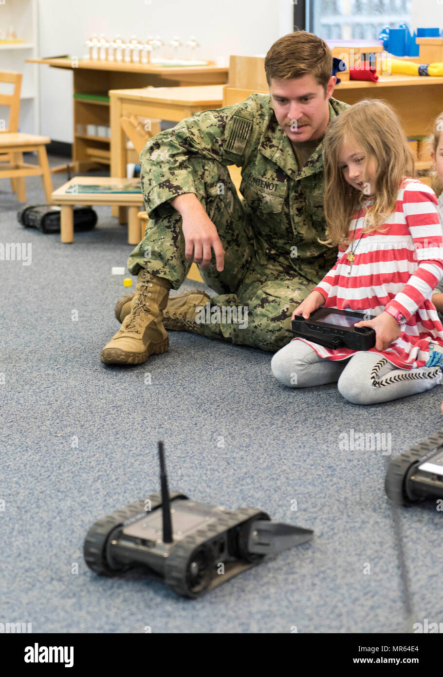 170512-N-SF508-041 NORFOLK, Va. (May 12, 2017) Explosive Ordnance Disposal Technician 2nd Class Nicholas Fontenot, assigned to Explosive Ordnance Disposal Mobile Unit (EODMU) 12, shows a student how to drive a Small Unmanned Ground Vehicle (SUGV) during a community relations event at McDonald Montessori School in Norfolk, Va. EODMU 12 provides credible, combat-ready EOD forces capable of deploying anywhere, anytime in support of national interests. (U.S. Navy photo by Mass Communication Specialist 2nd Charles Oki/Released) Stock Photo