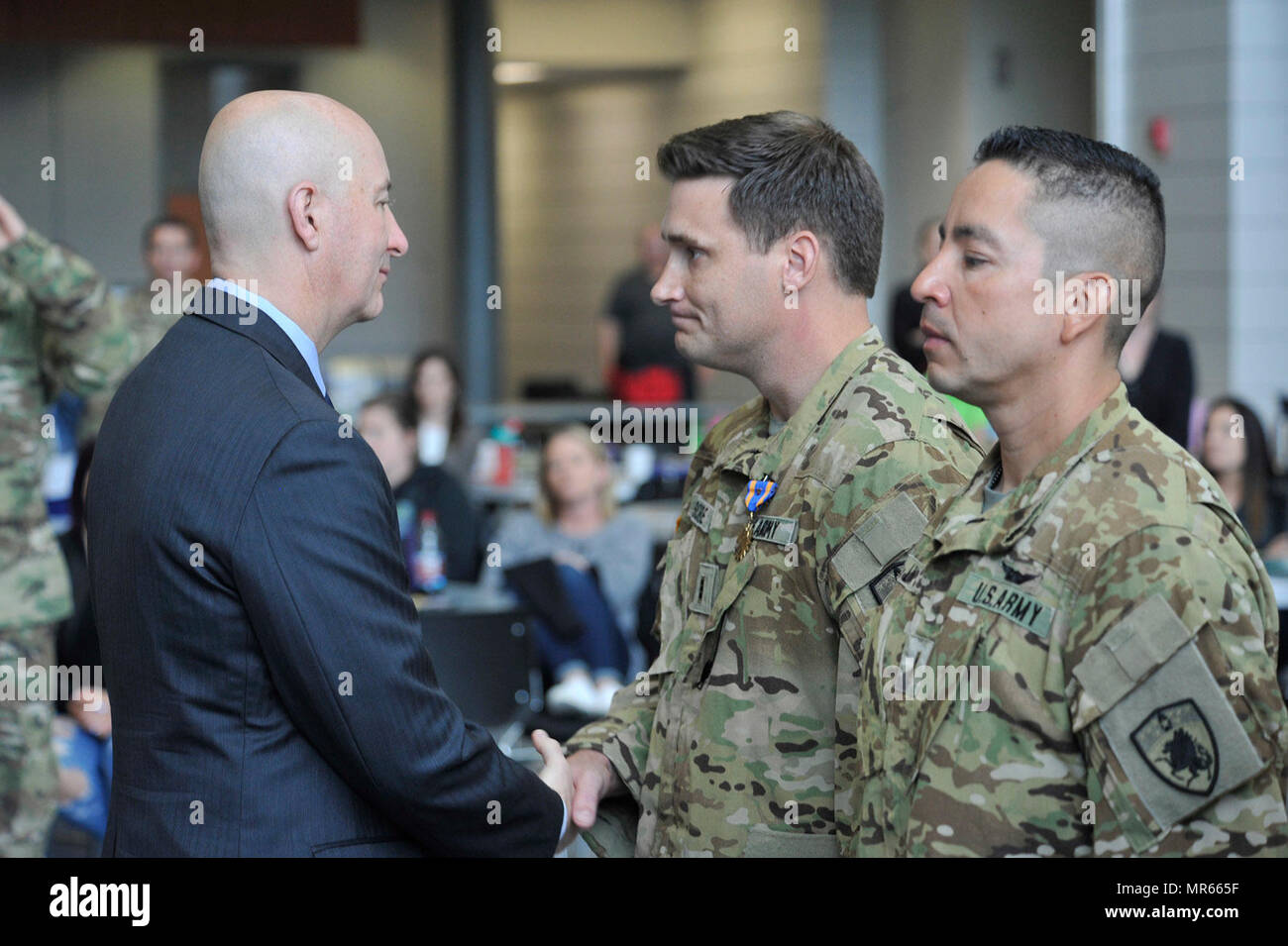 Nebraska Governor Pete Ricketts shakes the hand of Nebraska National Guard Chief Warrant Office 3 William Score (pilot) after pinning on a blue and gold Air Medal with a Valor device. Score was one of four Nebraska Army National Guard aviators assigned to a UH-60 Blackhawk helicopter crew who were honored, May 20, when they were presented with the Air Medal with “Valor” device for the bravery they displayed while rescuing a wounded U.S. Special Forces Soldier on Feb. 9, 2017, near Sangin, Afghanistan in the Helmund Province. The four Nebraska Army National Guard Soldiers are members of the Gua Stock Photo