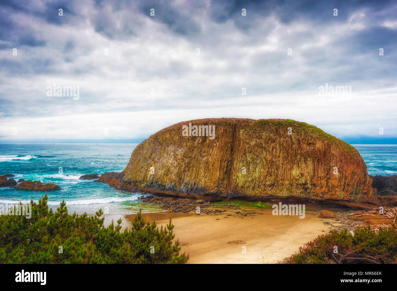 Oregon Coast Seal Rock stands majectic under marine and clouds layering the sky as one looks down from above with the tops of pine trees in the foregr Stock Photo