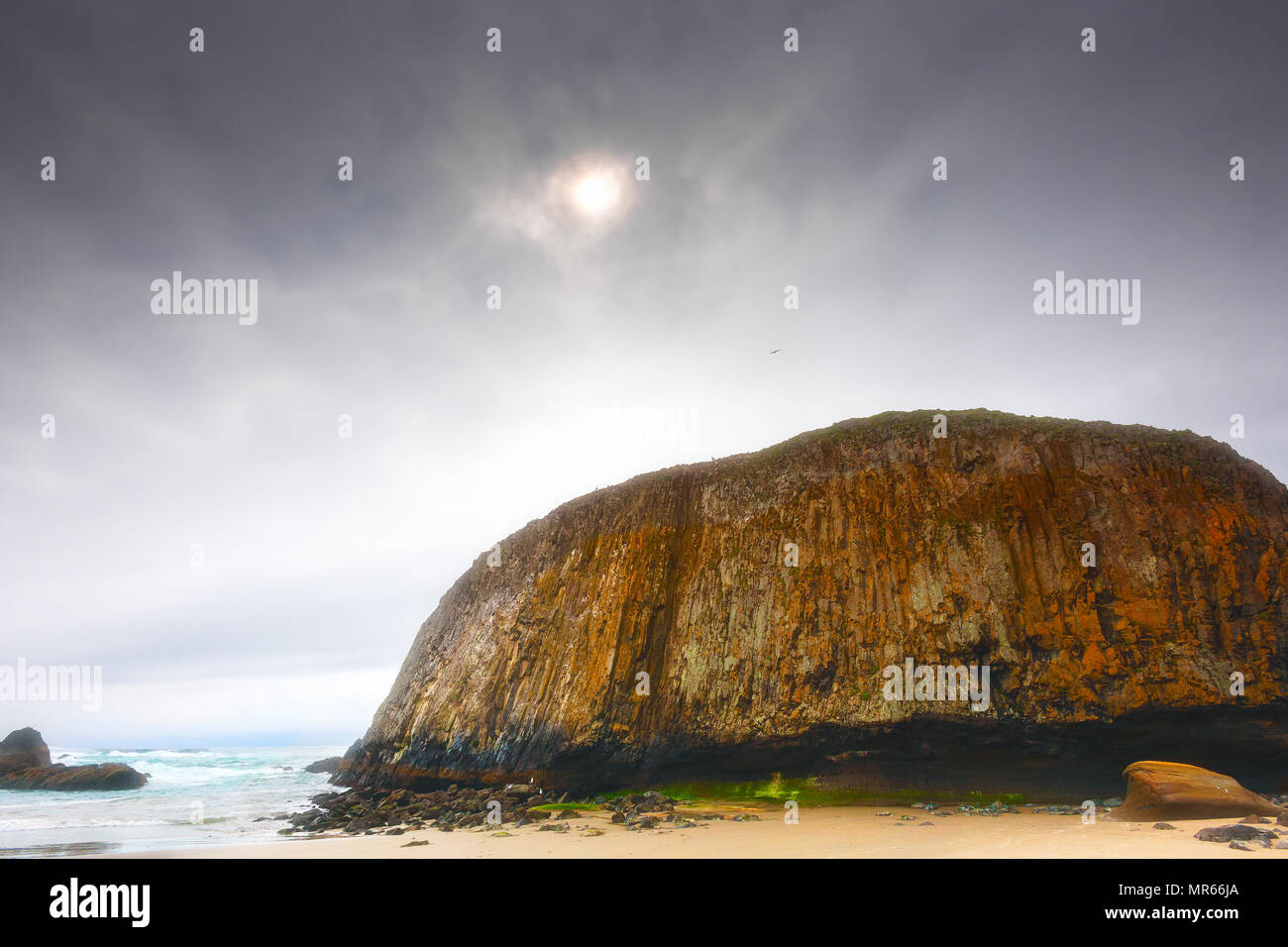Oregon Coast Seal Rock stands majectic under marine and cloude layered sky mutting the late afternoon sun. Stock Photo
