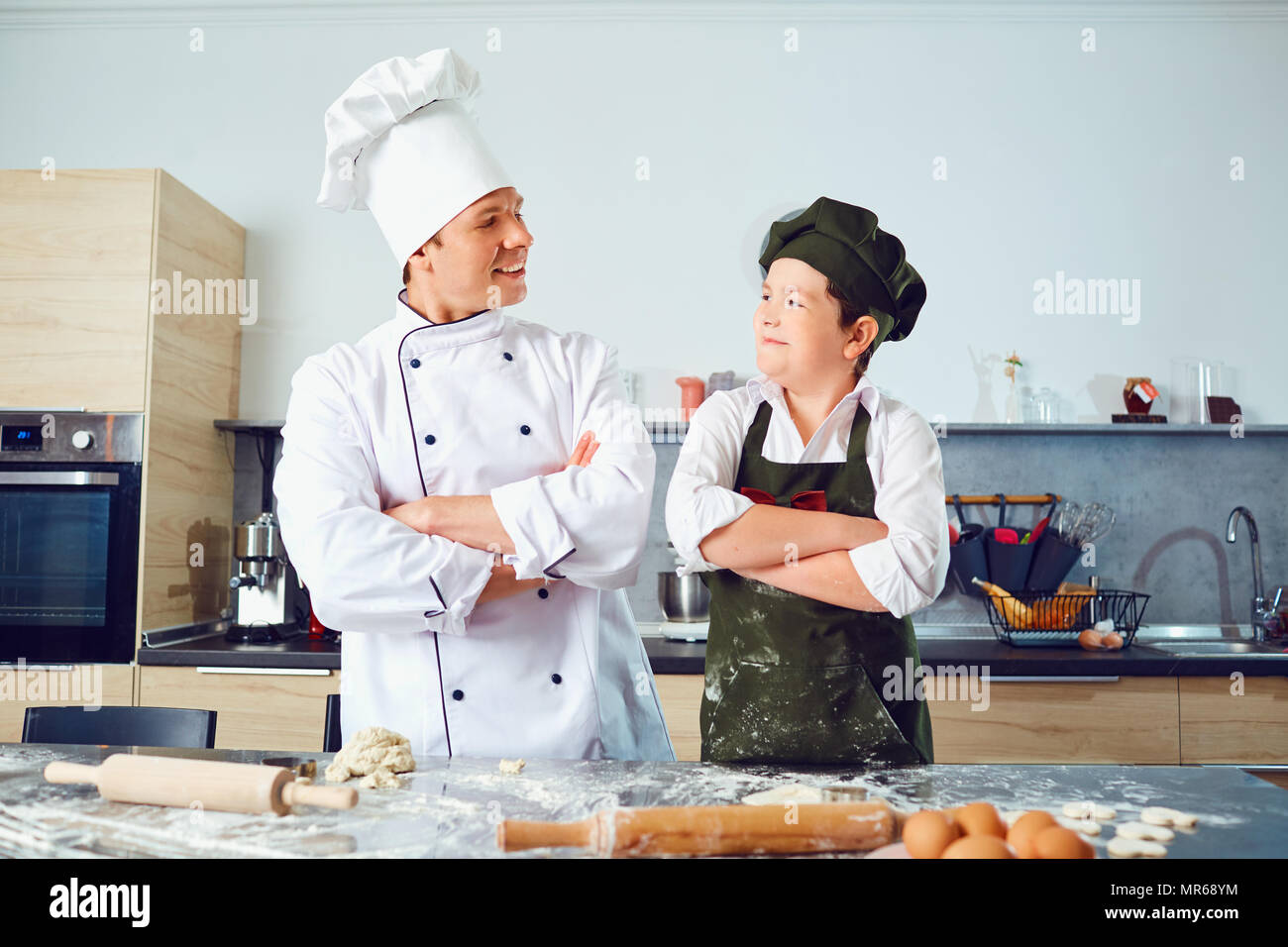 Cook with the boy in the uniform of the cook in the kitchen. Stock Photo