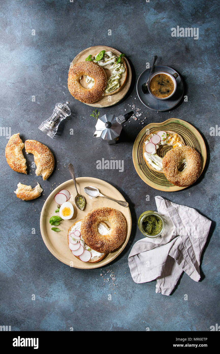 Variety of homemade bagels with sesame seeds, cream cheese, pesto sauce